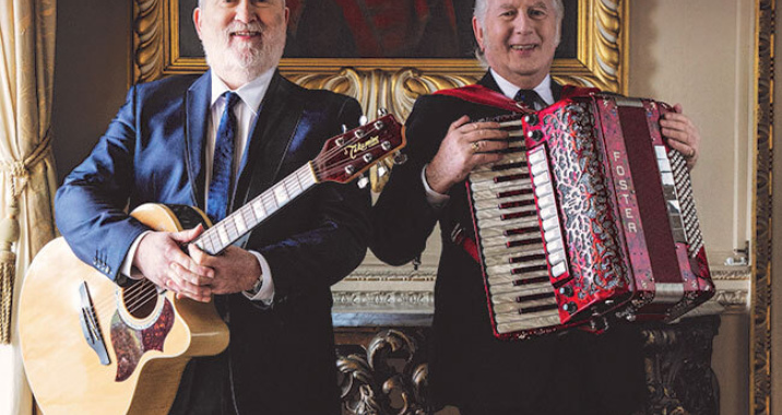 Two men, Foster and Allen, stand side by side, smiling, one holds an acoustic guitar, the other an accordion. Gold and white text above them reads 'Foster & Allen', 'We'll Meet Again', 'Irish Tour'.